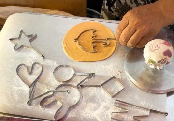 In this picture taken in Seoul on October 10, 2021, street vendor Lim Chang-joo stamps an umbrella shape onto a dalgona, a crisp sugar candy featured in the smash hit series Squid Game, for which he and his wife Jung Jung-soon were hired to be on set to make during production